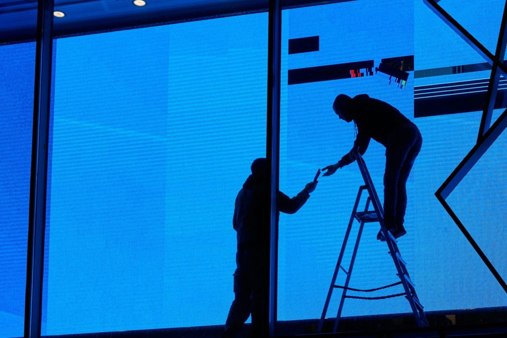 a man standing on a ladder next to a window