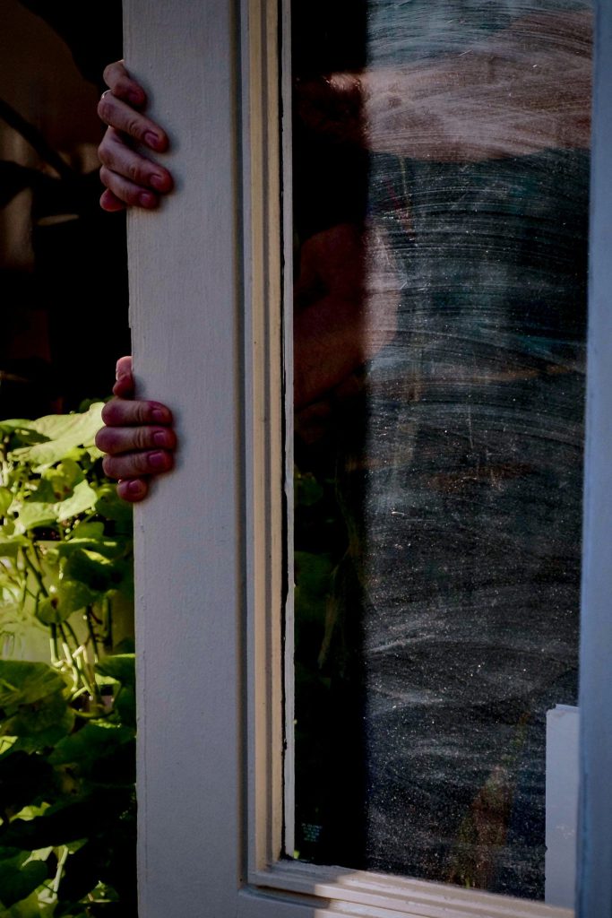 A person's hands holding onto the side of a window